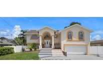 Tan two-story house with a two-car garage and landscaped yard at 15806 Adobe Dr, Hudson, FL 34667