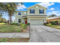 Two-story house with a green exterior, red door, and attached garage at 10724 Burning Bush Ter, Land O Lakes, FL 34638
