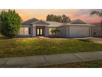 Single-story home with gray siding, two-car garage, and landscaped lawn at 3470 Cedar Crest Loop, Spring Hill, FL 34609