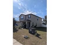 Two-story house with a tan exterior, landscaping, and a two-car garage at 8278 Silverbell Loop, Brooksville, FL 34613