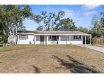 Charming ranch-style home with a white brick facade and covered porch at 27329 Azen Loop, Brooksville, FL 34602