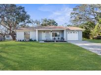 Newly renovated house with a landscaped lawn and a two-car garage at 3131 Deltona Blvd, Spring Hill, FL 34606