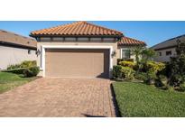 Tan house with tile roof, 2-car garage, and landscaped yard at 3312 Francoa Dr, Odessa, FL 33556