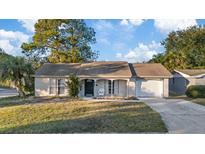 Tan single-story house with a brown roof, attached garage, and well-manicured lawn at 4151 Hillsdale Dr, New Port Richey, FL 34652