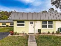 Light green house with gray metal roof, white door, and landscaped yard at 11722 Carissa Ln # 49A, New Port Richey, FL 34654