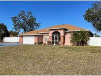 Brick house with brown roof, screened porch, and fenced backyard at 15131 Eastwood Trl, Brooksville, FL 34604