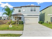 Two-story house with light blue siding, two-car garage, and landscaping at 313 Argyll Dr, Spring Hill, FL 34609