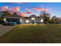 White house with a black door, two-car garage, and well-manicured lawn at 2510 Whitewood Ave, Spring Hill, FL 34609