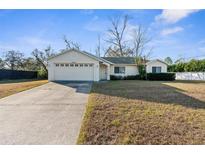 Bright white house with a two-car garage and a spacious lawn at 3047 Fairview Rd, Spring Hill, FL 34609