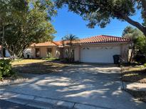 Spanish style home with tile roof, attached garage, and well-manicured lawn at 3151 Carlos Dr, Dunedin, FL 34698