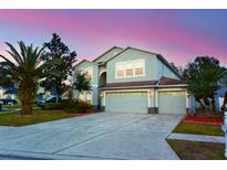 Two-story house with a three-car garage and landscaped lawn at 4634 Mapletree Loop, Wesley Chapel, FL 33544