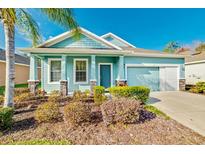 Charming one-story home with light blue siding, landscaping, and a two-car garage at 11041 Paradise Point Way, New Port Richey, FL 34654