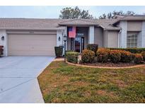 Brick front exterior of house with 2 car garage, American flag, and landscaping at 18049 Tarrington Pl, Hudson, FL 34667