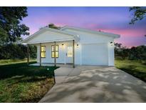 White house with a front porch, attached garage, and a well-manicured lawn at 4067 Monona Ave, Spring Hill, FL 34606
