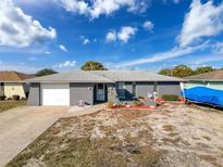 Gray house with white garage door, landscaping, and boat at 7345 Fireside Dr, Port Richey, FL 34668