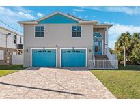 Two-story house with teal accents, two-car garage, and a paved driveway at 3215 Rose Arbor Dr, Hernando Beach, FL 34607