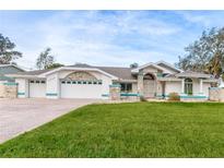 A beautifully landscaped single-Gathering home featuring an attached three-car garage and stone accents at 5286 Hamlet Cir, Spring Hill, FL 34606