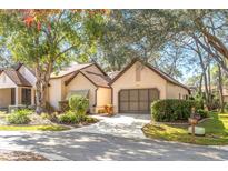 Tan single-story house with brown roof, garage, and mature landscaping at 6663 Water Oak Ct, Spring Hill, FL 34606