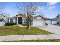 House exterior features a three-car garage and well-manicured lawn at 7448 Mengi Cir, New Port Richey, FL 34653