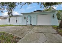 Light blue house with a white garage door and stone accents at 9744 Rainelle Ln, Port Richey, FL 34668