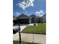 Charming single-story home with blue exterior, landscaped yard, and a dark brown garage door at 10722 Firebrick Ct, Trinity, FL 34655