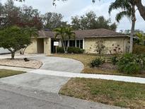 Tan house with brown roof, landscaping, and a curved driveway at 3039 Sandpiper Ct, Clearwater, FL 33762