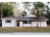 White single story home with brown trim, covered porch, and palm tree at 4852 Capron St, New Port Richey, FL 34653