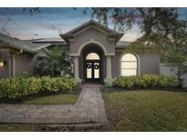 Gray house with double doors, walkway, and landscaping at 609 Salt Lake Dr, Tarpon Springs, FL 34689