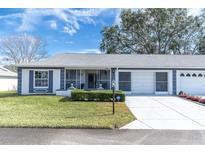 Front view of a single story home with a two car garage and screened porch at 11030 Linkside Dr # 11030, Port Richey, FL 34668