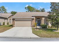 Brick house with 2-car garage, mature landscaping, and a large driveway at 1392 Summerwood Ct, Spring Hill, FL 34606