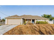 Tan one-story house with gray roof, attached garage, and landscaped yard at 4372 Odin St, Spring Hill, FL 34608