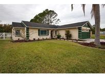 Single-story house with green accents, mature landscaping, and a spacious yard at 4649 Westerly Dr, New Port Richey, FL 34653
