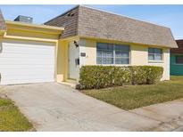 Cute yellow house with a white garage door and well-manicured lawn at 7037 Versailles N # 15, Pinellas Park, FL 33781