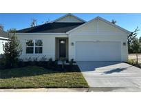 One-story home with white exterior, two-car garage, and landscaped front yard at 10123 Zennia Ln, Parrish, FL 34219