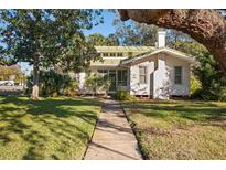 Charming white house with green roof, spacious yard, and walkway at 106 Banana St, Tarpon Springs, FL 34689