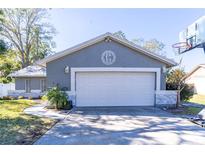 Gray house with white garage door, stone accents, and a basketball hoop in the yard at 14004 Cascade Ln, Tampa, FL 33618