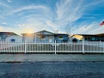 Charming single-story home featuring a white picket fence and a well-manicured lawn at 1415 Weyford Ln, Holiday, FL 34691