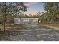Single-wide manufactured home with a gravel driveway and mature trees at 3323 Parlow Ave, Spring Hill, FL 34606