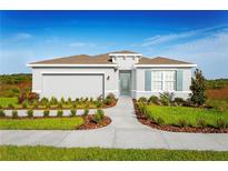One-story home with gray exterior, brown roof, and landscaped yard at 6027 Wild Petunia Dr, Wimauma, FL 33598