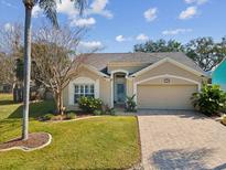 Charming single-story home with landscaped yard, brick driveway, and neutral-toned exterior paint at 1758 Biarritz Cir, Tarpon Springs, FL 34689