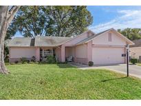 Pink one-story house with a two-car garage and well-maintained lawn at 2263 Whisper Walk Dr, Spring Hill, FL 34606