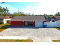 Charming single-story home with a red exterior, gray roof, covered entry, and a spacious paved driveway at 14006 Arbor Knoll Cir, Tampa, FL 33625
