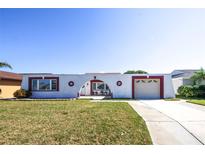 Unique single-story home with an arch detail over the entryway and garage, surrounded by a green lawn at 3526 Overland Dr, Holiday, FL 34691
