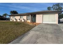 Charming single-story home with a well-maintained lawn and a paved driveway leading to an attached two-car garage at 4115 Corn St, Port Charlotte, FL 33948