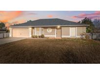 Tan single-story home with a garage, neutral trim, and well-maintained gray roof at 5155 Baldock Ave, Spring Hill, FL 34608