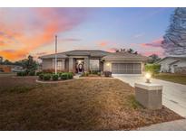 Charming single-story home featuring manicured landscaping, a two-car garage, and a warm, inviting entryway at 6112 Kinlock Ave, Spring Hill, FL 34608