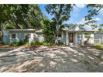 Charming single-story home featuring a red front door, light blue paint, stone trim, and lush landscaping at 1101 N Betty Ln, Clearwater, FL 33755