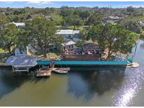 An aerial view of a waterfront home with a dock, boat lift, and an outdoor living space on the water at 7235 Maryland Ave, Hudson, FL 34667