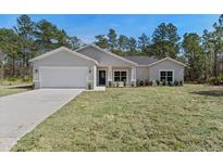 Charming single-story home featuring a two-car garage, well-manicured lawn, and inviting front entrance at 18020 Macek Rd, Weeki Wachee, FL 34614