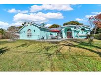 Charming turquoise home with a well-manicured lawn and a bright red front door, perfect for a Gathering at 2334 Gimlet, Spring Hill, FL 34608